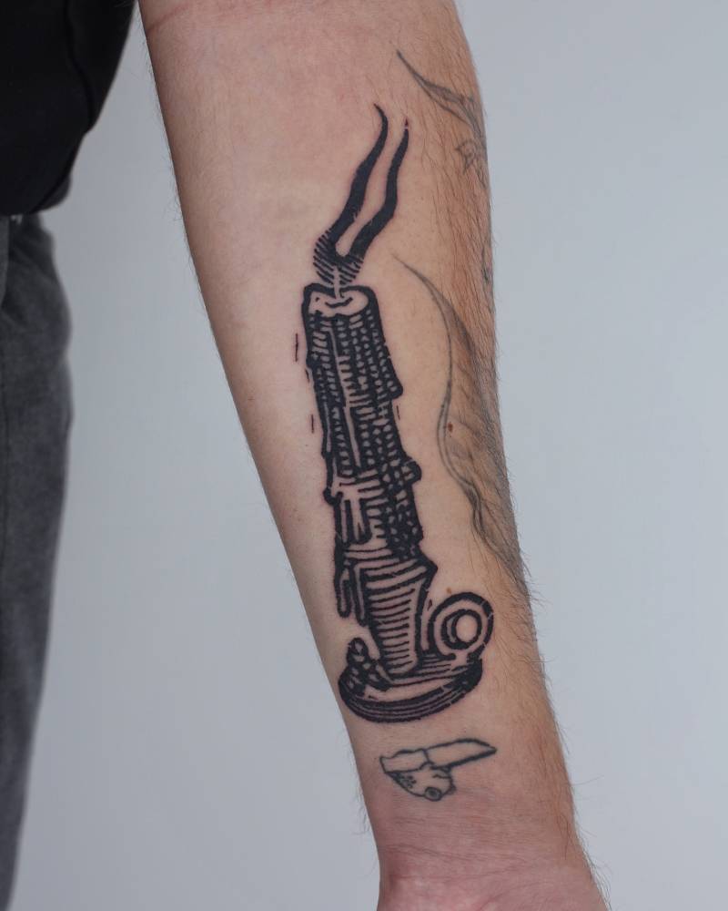 Candle tattoo in blackwork style placed on the inner forearm.