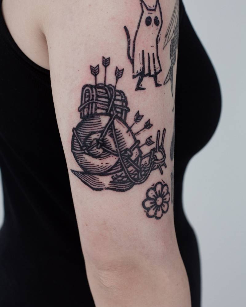 Snail tattoo in engraving style located on the upper arm.