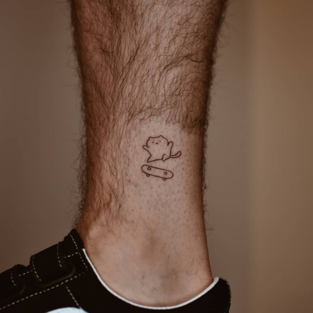 Fine line style skater cat tattoo placed on the ankle.