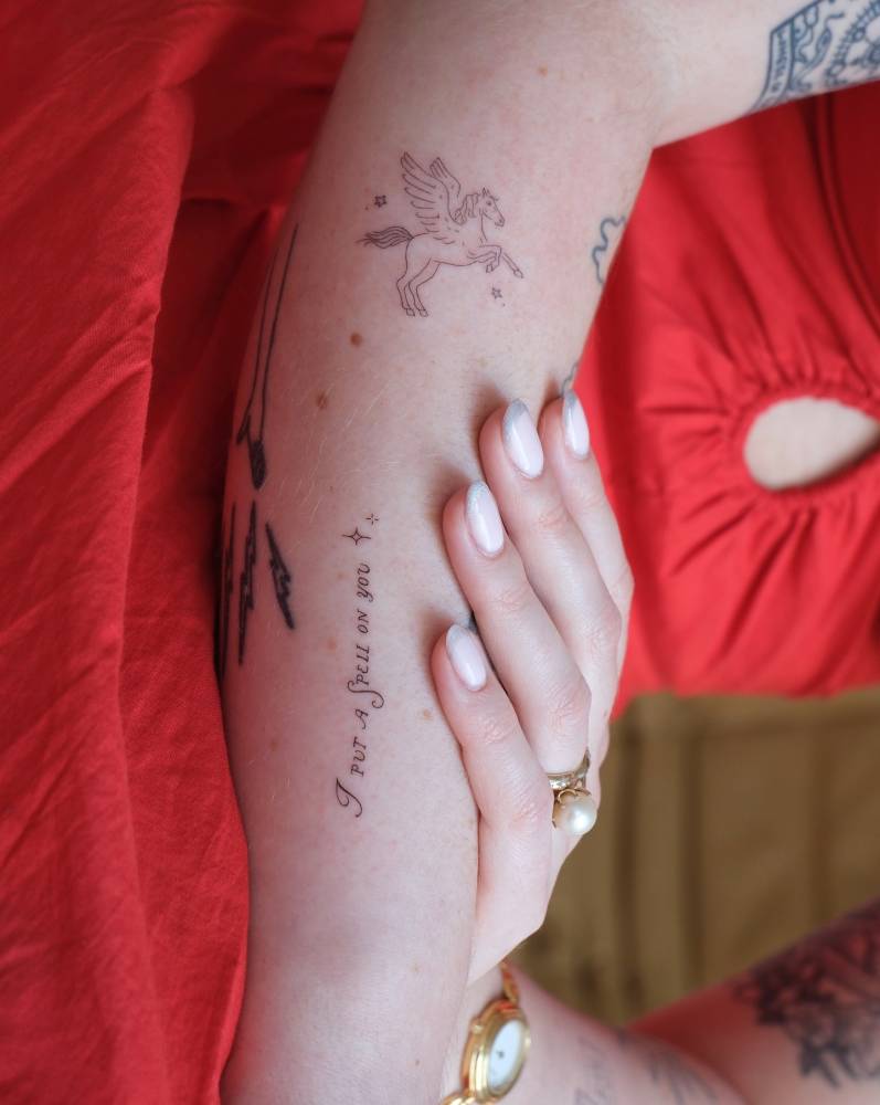 Fine line unicorn and "I put a spell on you" tattoos located on the forearm.