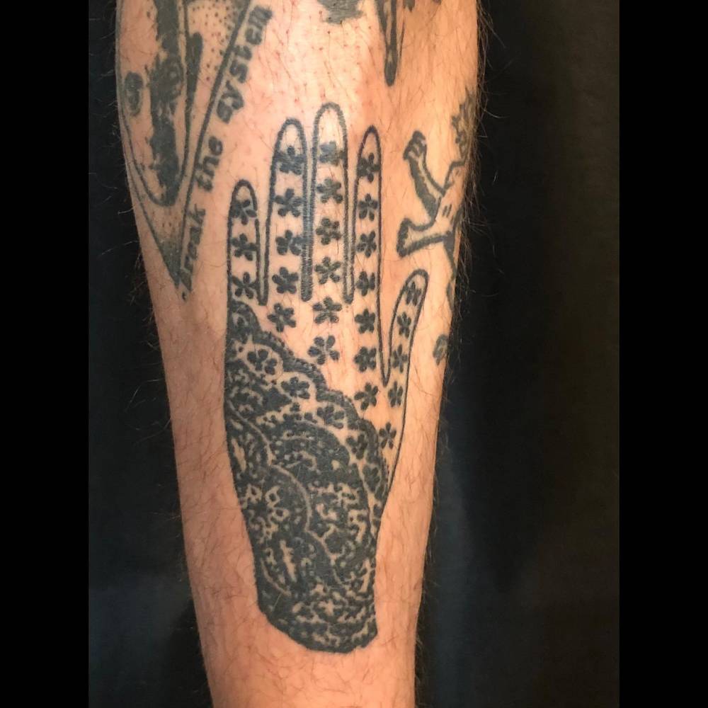 Healed glove tattoo in blackwork style located on the shin.