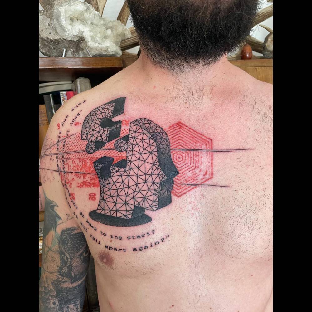 Graphic style puzzle piece and head tattoo located on the chest.