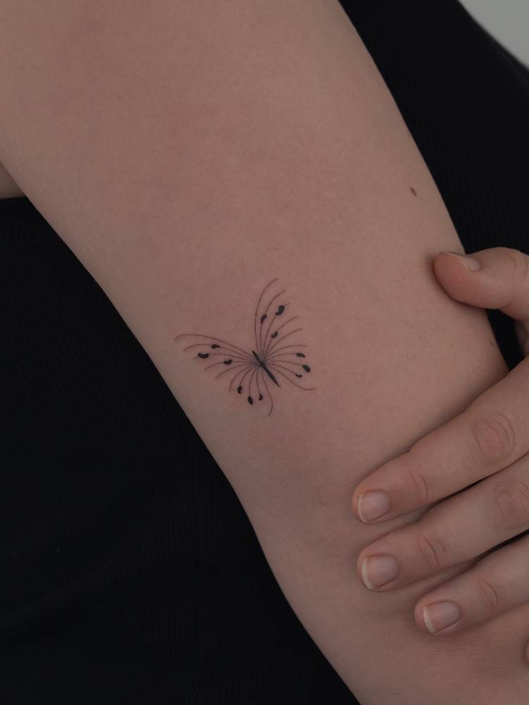 Single needle butterfly tattoo located on the tricep.