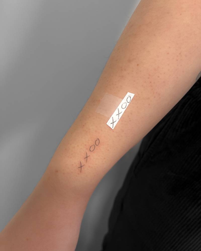 "XXOO" lettering tattoo located on the wrist.