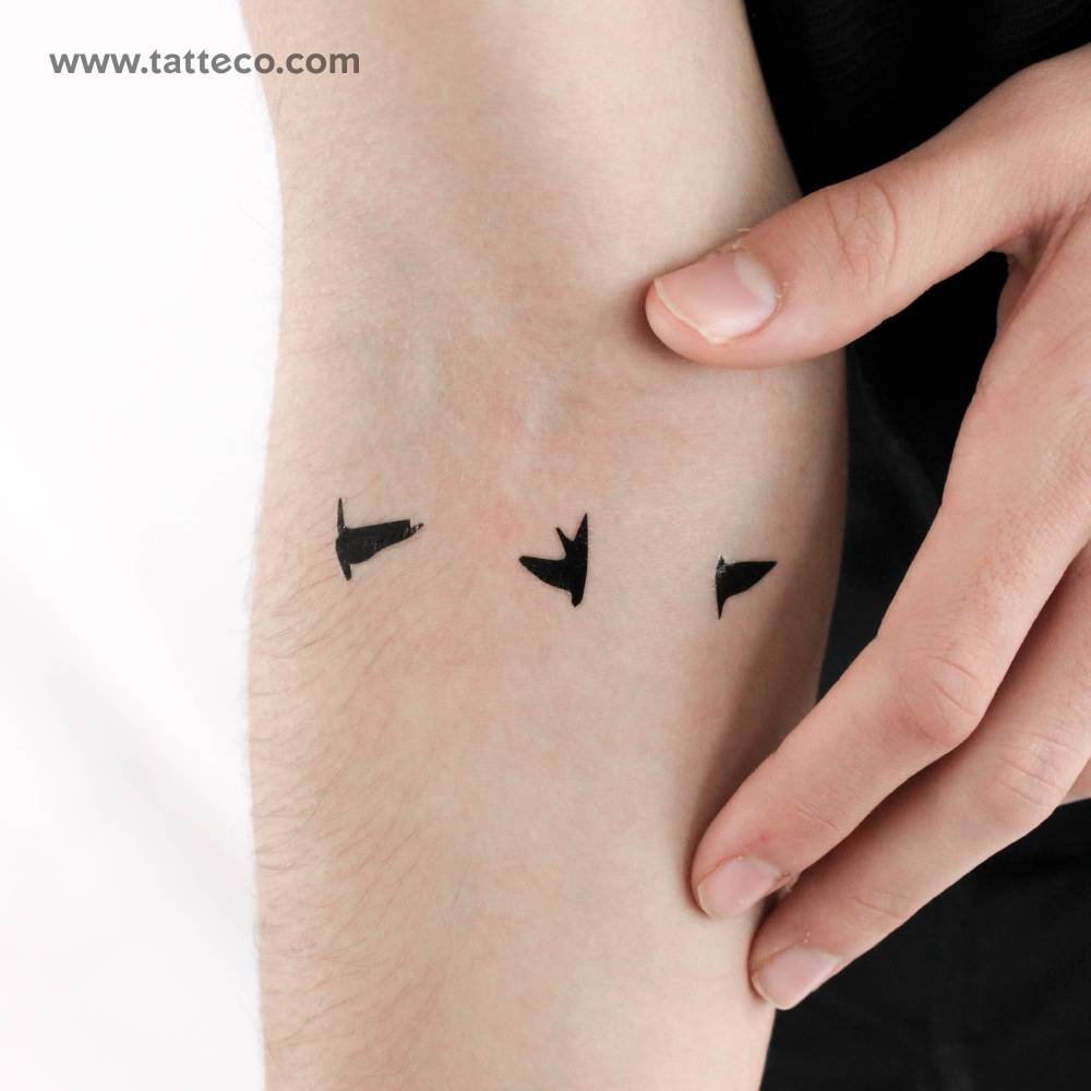 Minimalistic style three flying birds temporary tattoo located on the inner forearm.