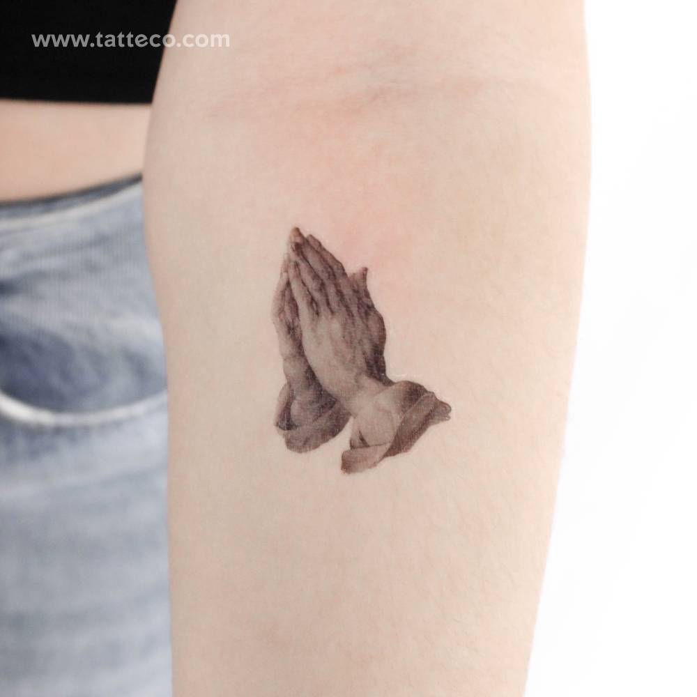 Micro-realistic style 'Praying Hands' temporary tattoo placed on the inner forearm.
