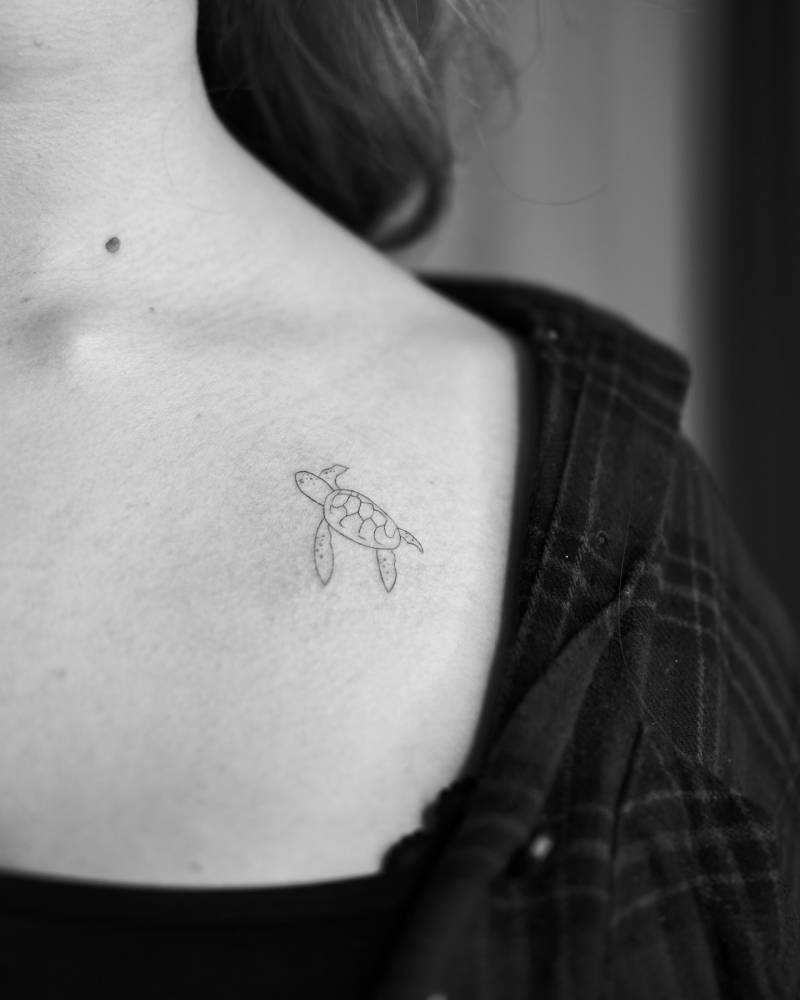 Turtle tattoo in fine line style placed on the collarbone.