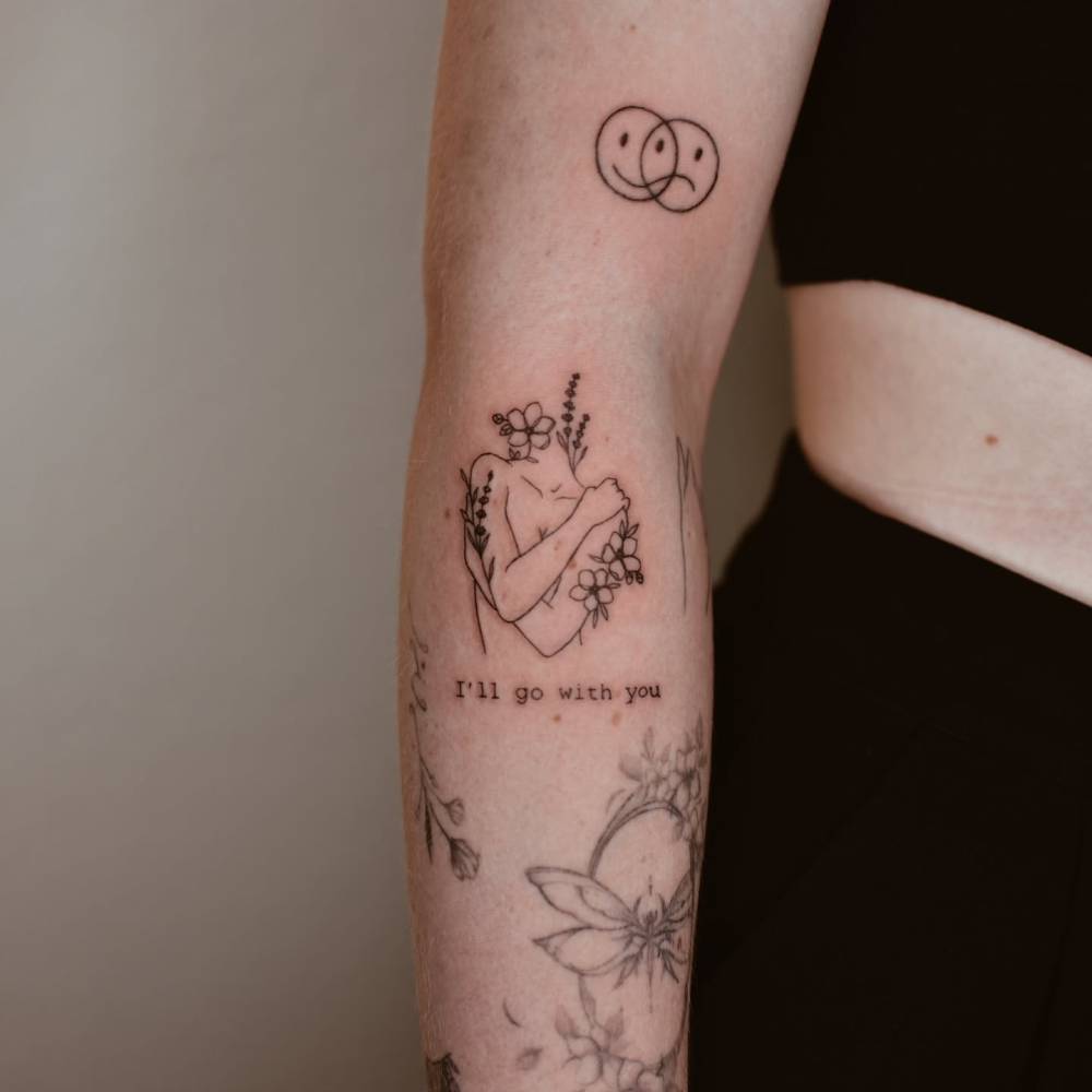 Flower head woman tattoo located on the forearm.