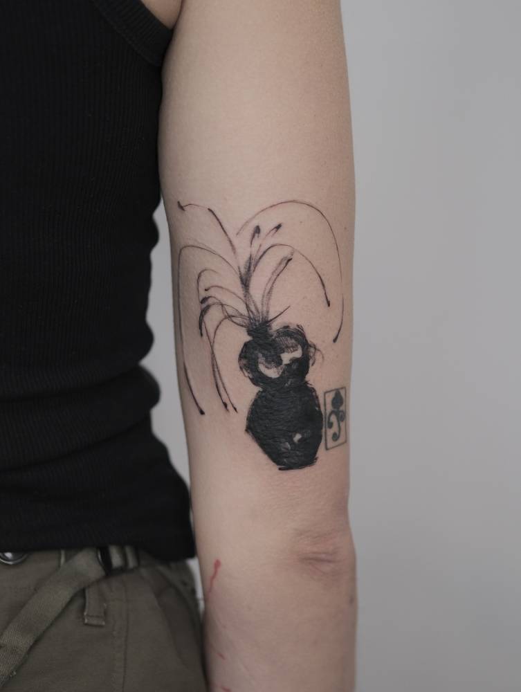 Blackwork style plant vase tattoo located on the tricep.