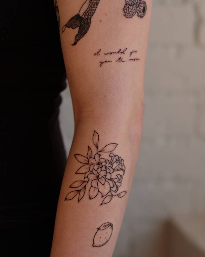Illustrative style floral tattoo located on the forearm.