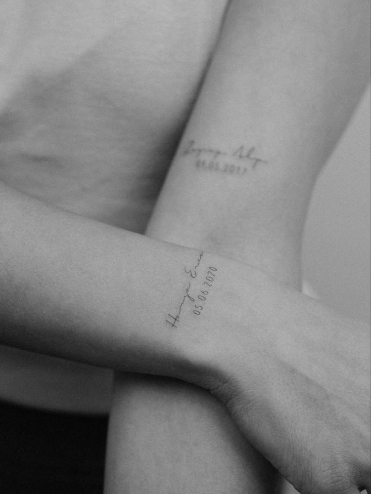 Name and date tattoo handwritten on the wrist.