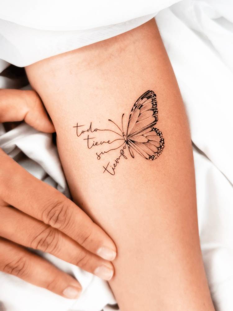 "Todo tiene su tiempo" and butterfly tattoo located on the inner forearm.