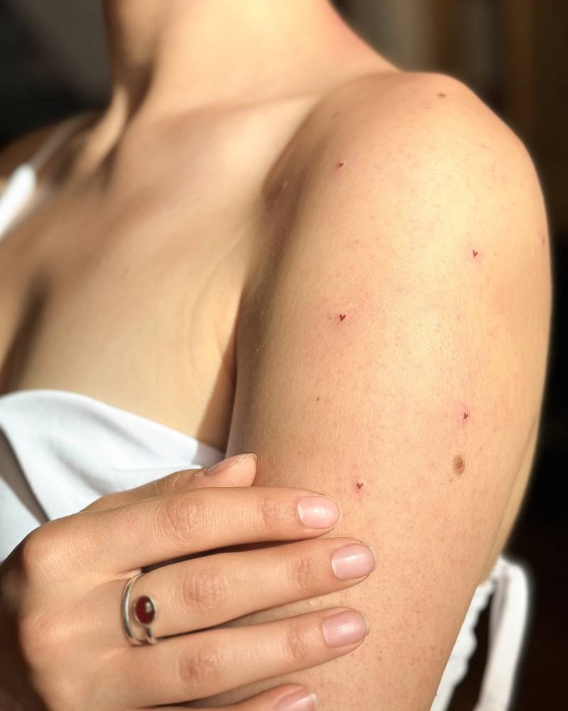 Minimalistic style heart freckles tattooed on the upper arm.