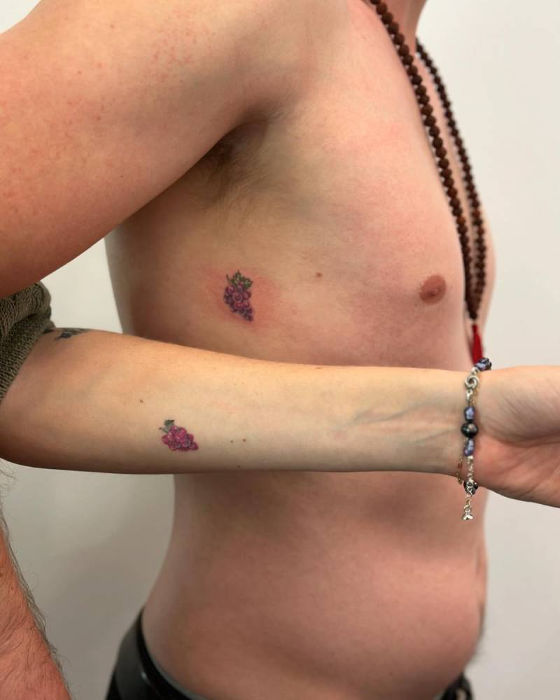 Matching illustrative style grapes tattoo for couple.