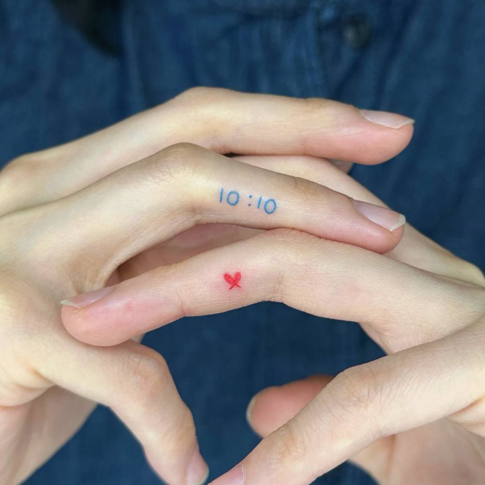Hour and red heart tattoos located on the fingers.