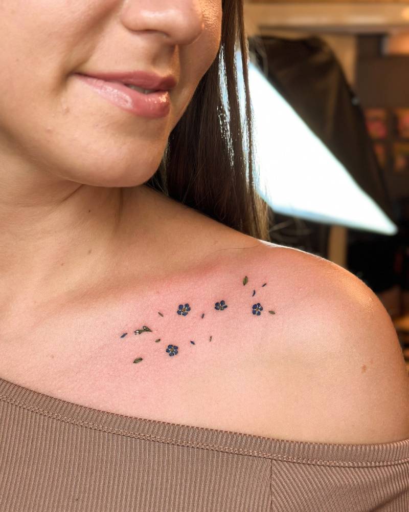 Forget-me-not flowers tattooed collarbone, done in watercolor style.