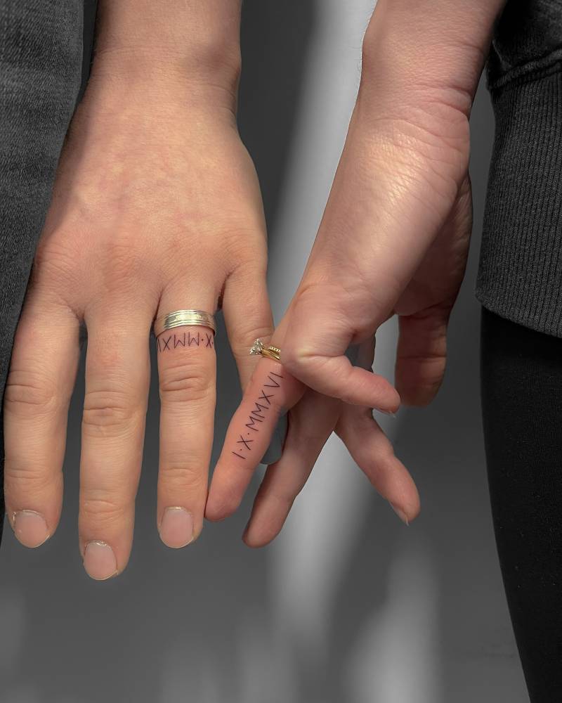 Matching dates in roman numerals tattooed for couple.