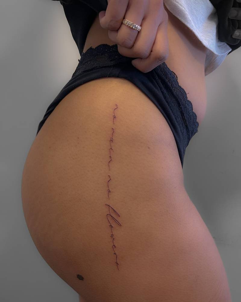 Handwritten font "no rain, no flowers" lettering tattoo located on the hip.