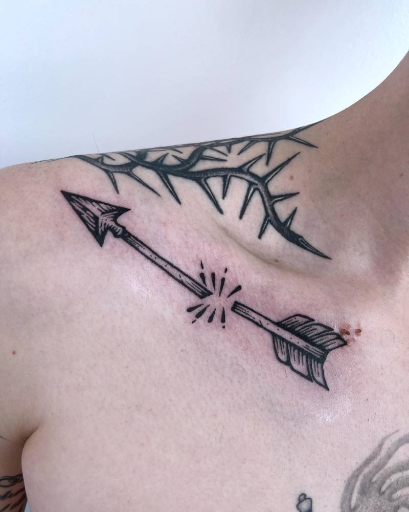 Broken arrow tattoo in engraving style located on the collarbone.