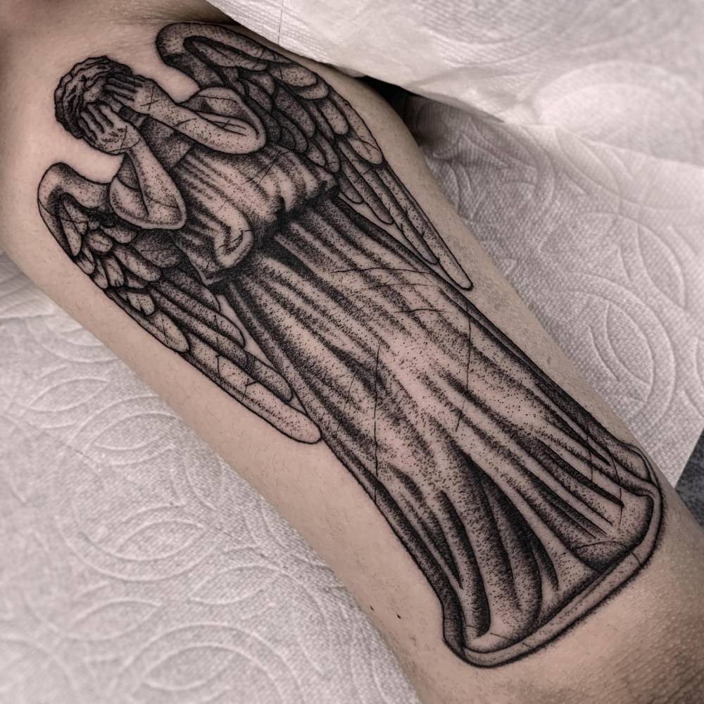 Angel tattoo in blackwork style located on the tricep.