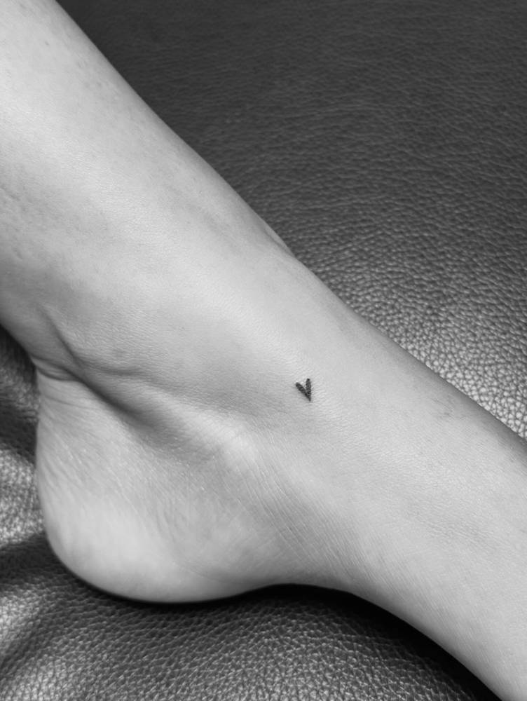 Tiny minimalistic heart tattoo located on the foot.