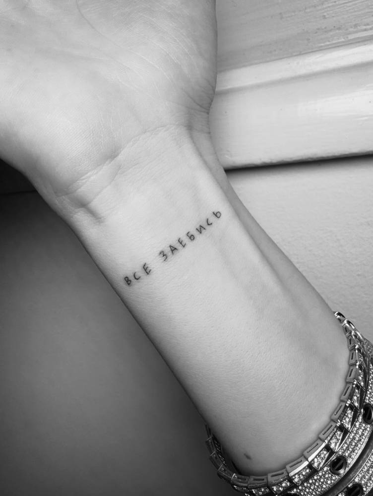 Russian quote tattoo located on the wrist.