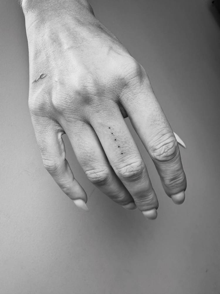 Tiny minimalistic dots tattoo located on the finger.