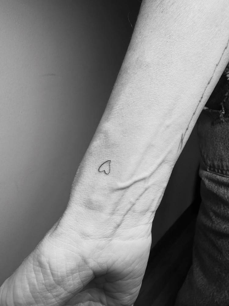 Little heart tattoo placed on the wrist, minimalistic style.