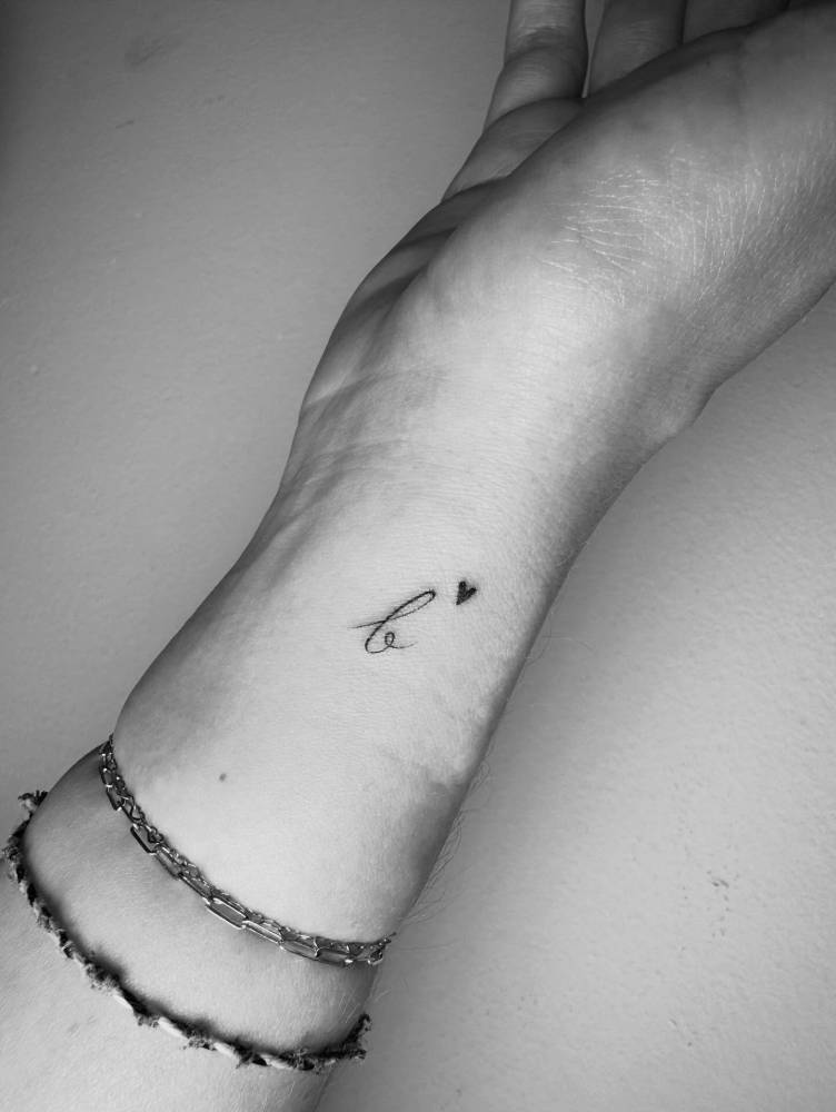 Letter "B" and minimalistic heart tattooed on the wrist.