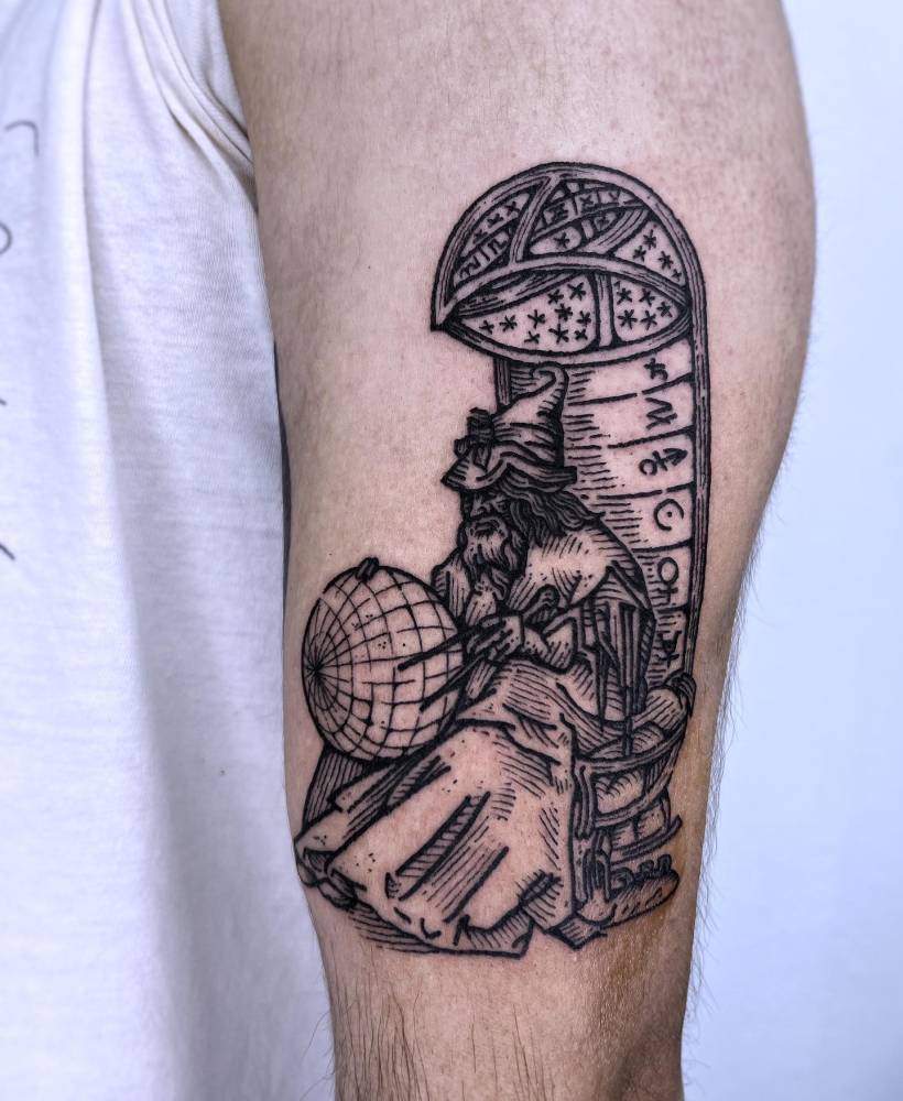 Wizard tattoo in engraving style placed on the upper arm.