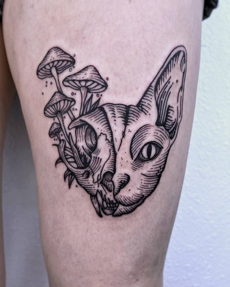 Cat skull and mushrooms tattoo placed on the thigh, done in engraving style.