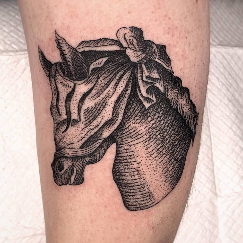 Horse head tattoo in engraving style located on the inner arm.