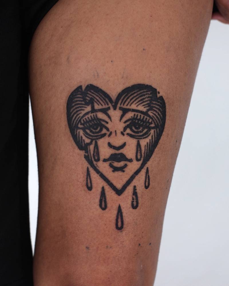 Blackwork style crying heart tattoo located on the thigh.