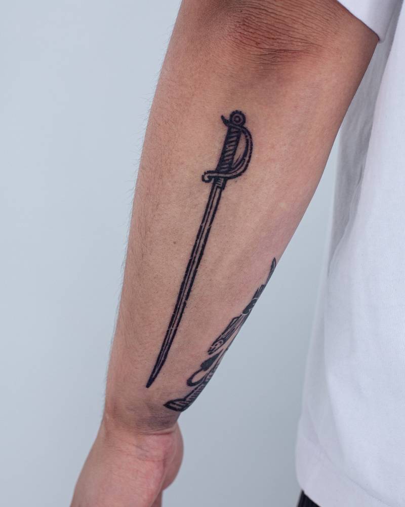 Sword tattoo in engraving style done on the forearm.