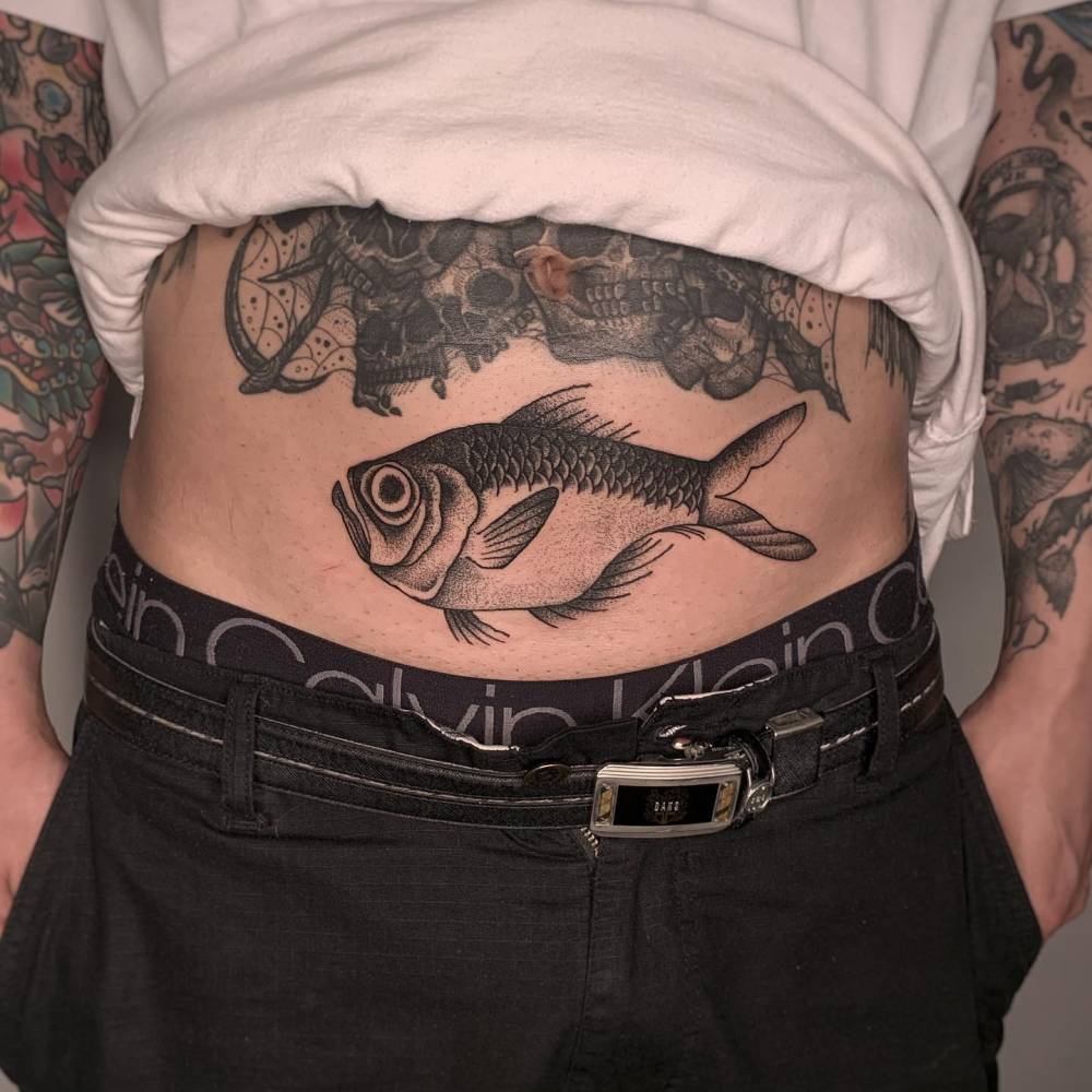 Blackwork style fish tattoo located on the stomach.
