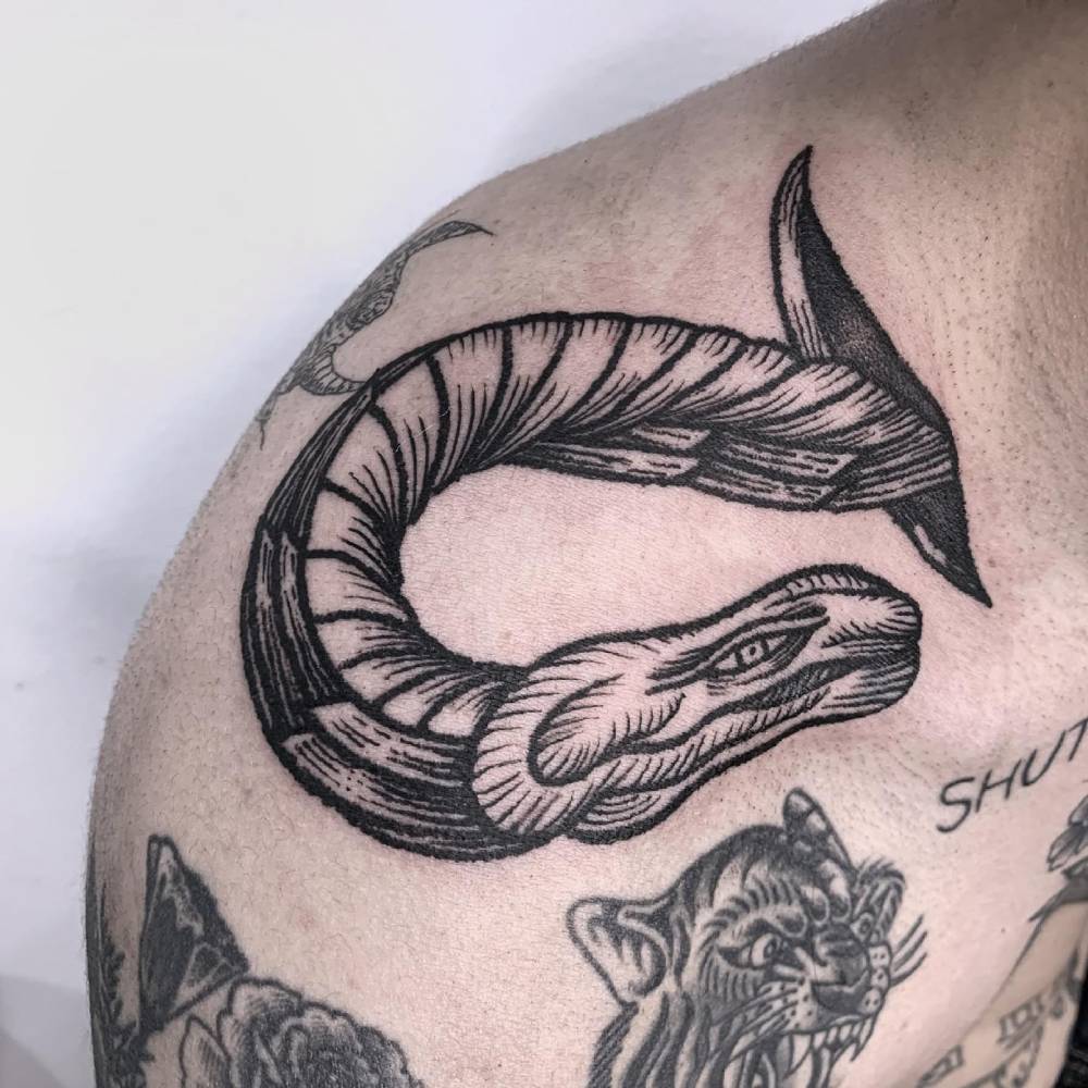 Snake tattoo in engraving style located on the top of shoulder.