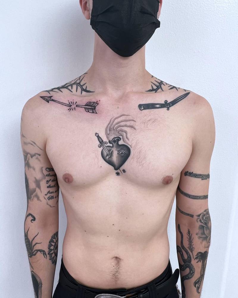 Flaming heart tattoo in blackwork style placed on the sternum.