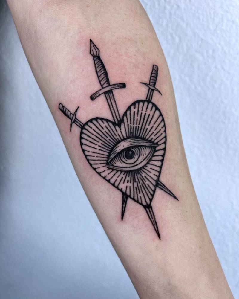 Heart and dagger tattoo in blackwork style placed on the inner forearm.