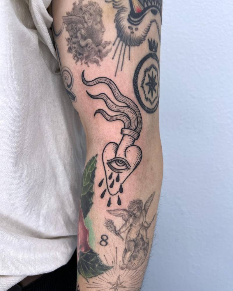 Crying flaming heart gap filler tattoo done on the elbow.