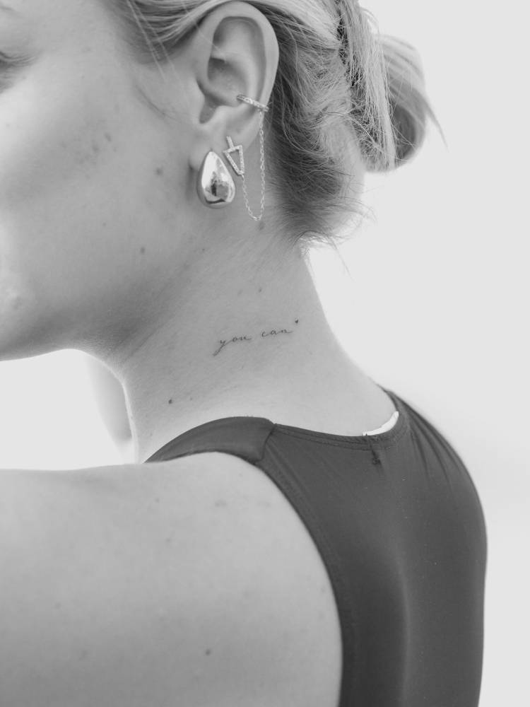 Lettering tattoo that says "you can" located on the neck.