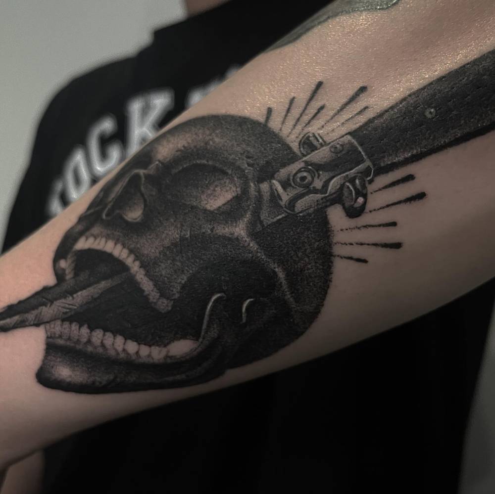 Skull and switchblade knife tattoo located on the forearm.