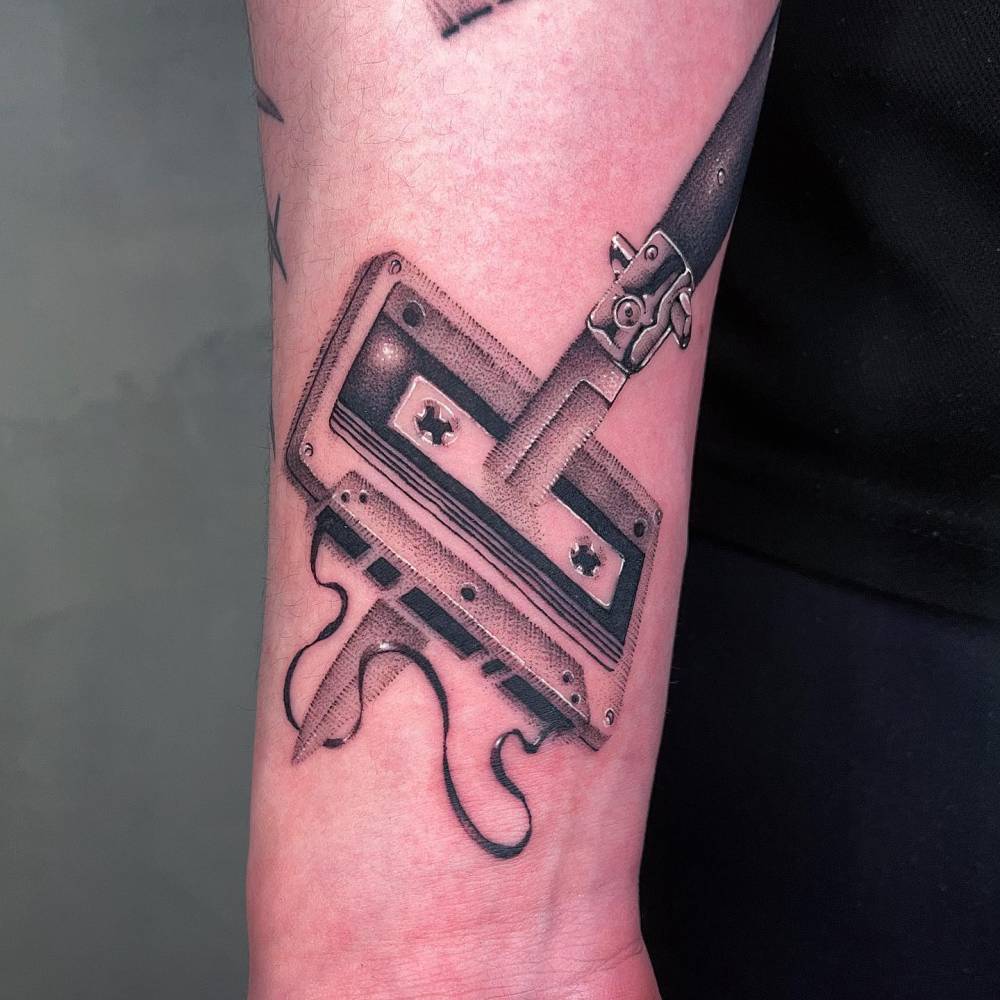 Dotwork style switchblade an cassette tape tattoo located on the wrist.