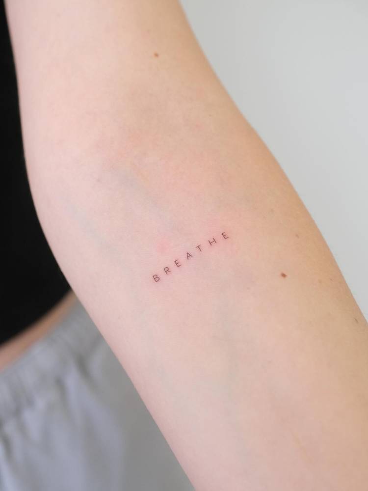 Lettering tattoo of the word "breathe" located on the inner forearm.