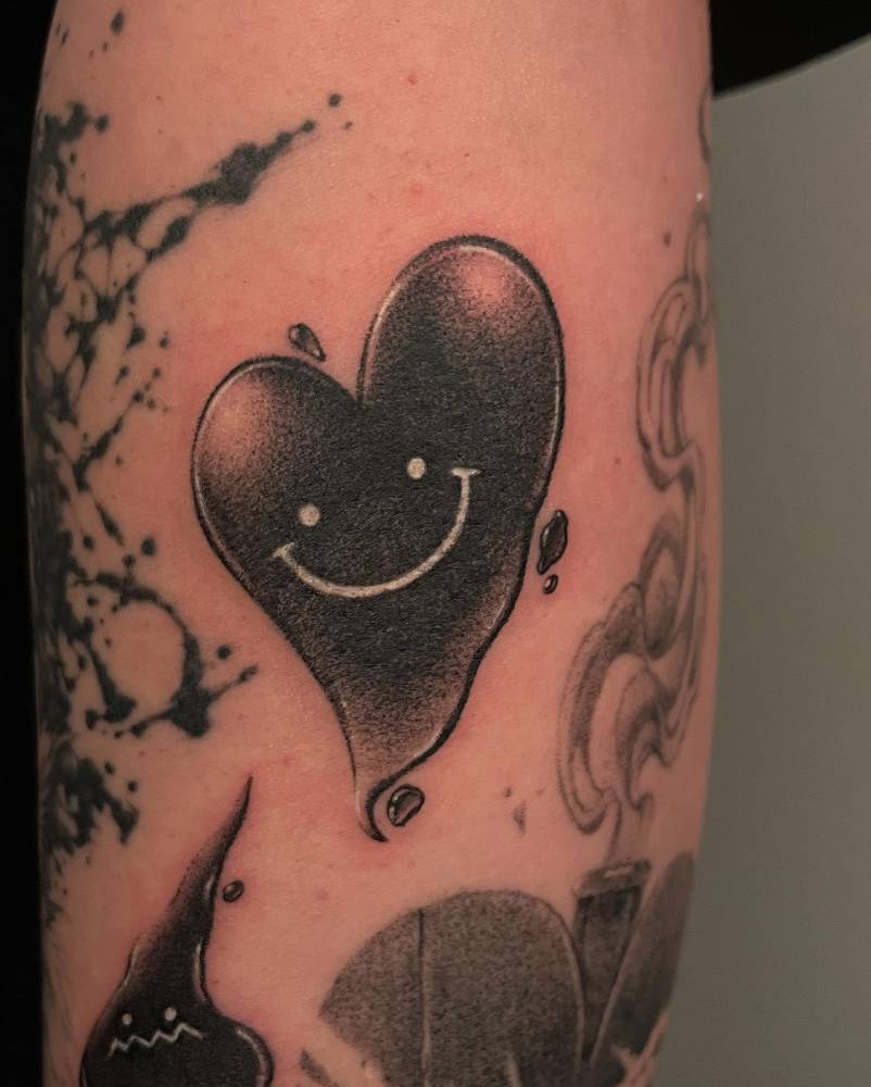 Smiley heart tattoo in dotwork style located on the forearm.