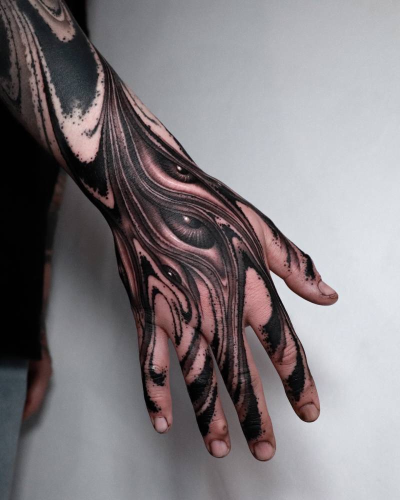 Abstract eyes tattoo located on the hand, done in blackwork style.