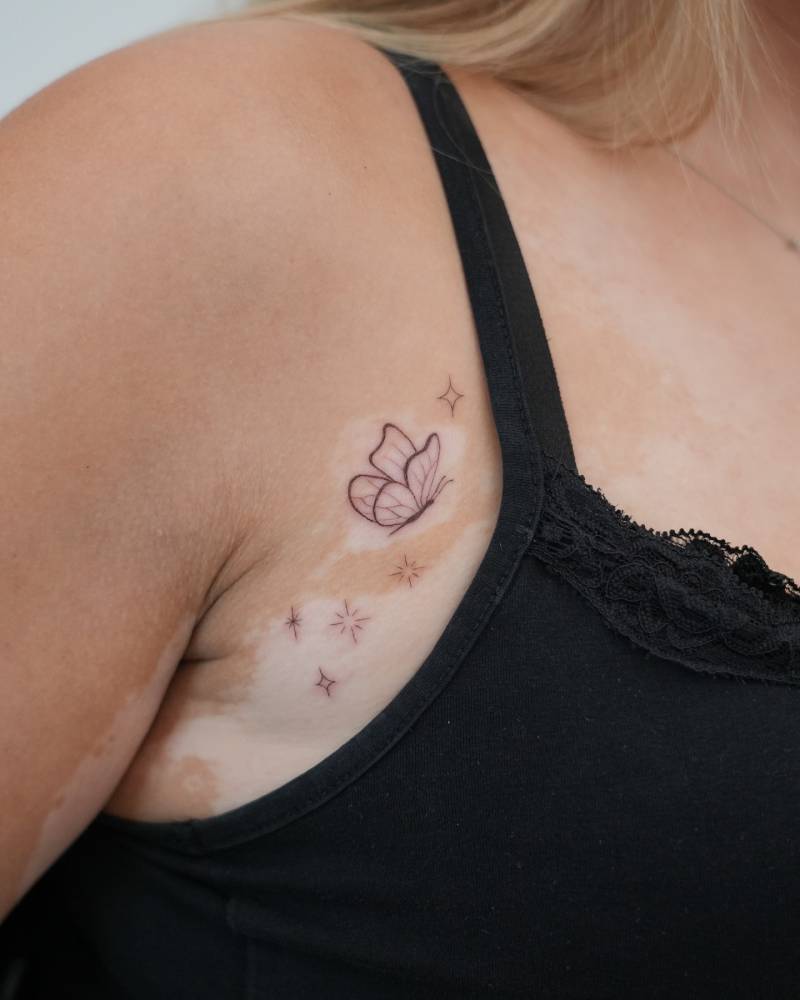 Butterfly and sparkling stars tattoo located on the breast.