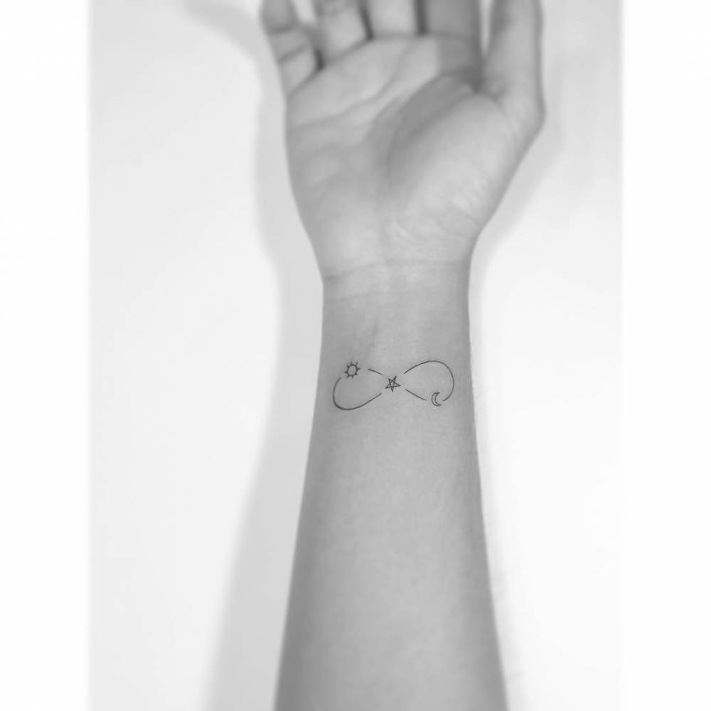 Infinity symbol, sun, star and moon tattoo located on the wrist.
