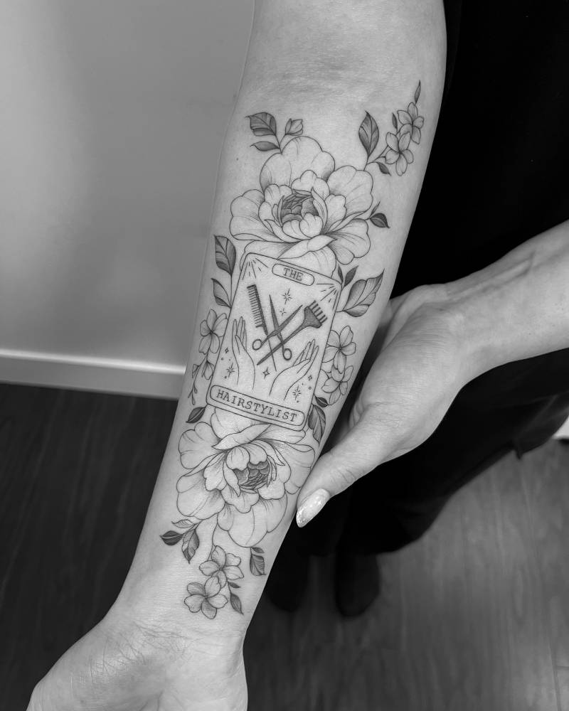 Illustrative style peonies and hairdresser tarot card tattoo located on the inner forearm.