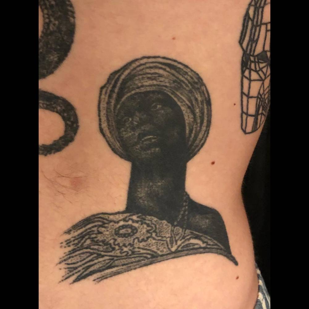 Healed tribal African woman portrait tattoo located on the waist.
