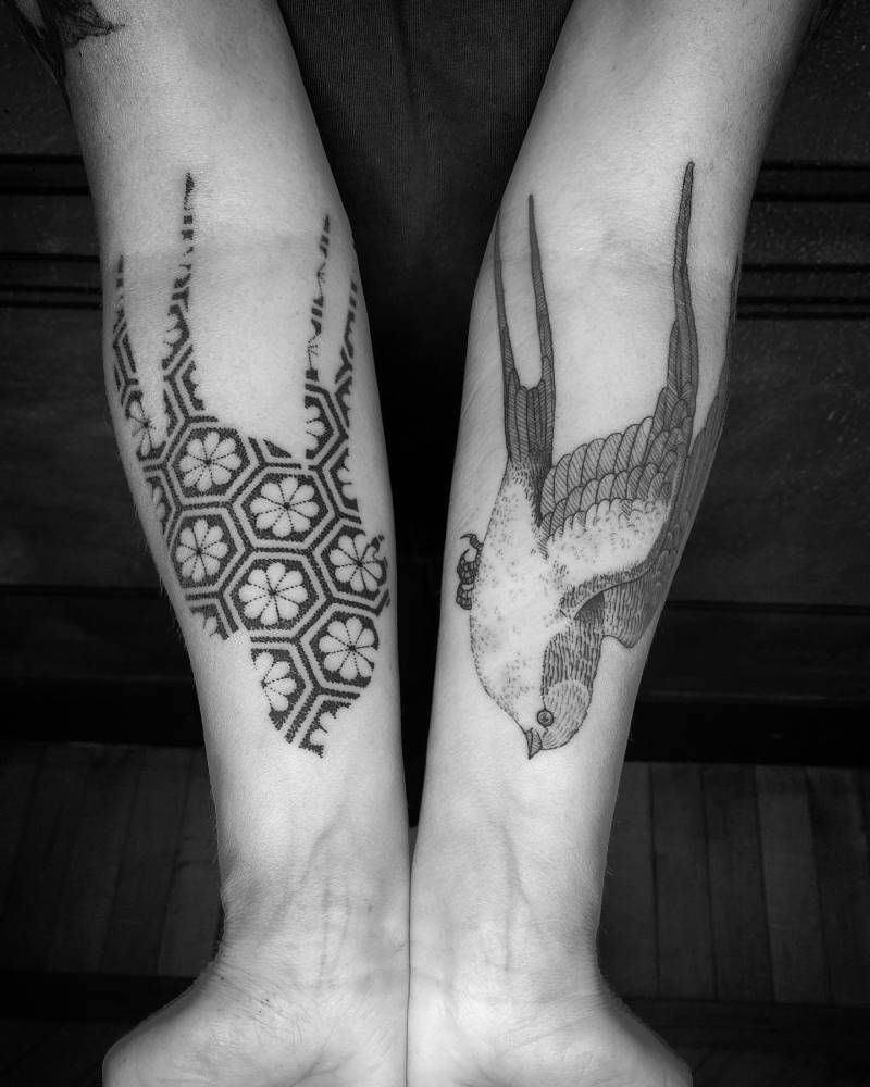 Individual matching swallows tattooed on the inner forearms.